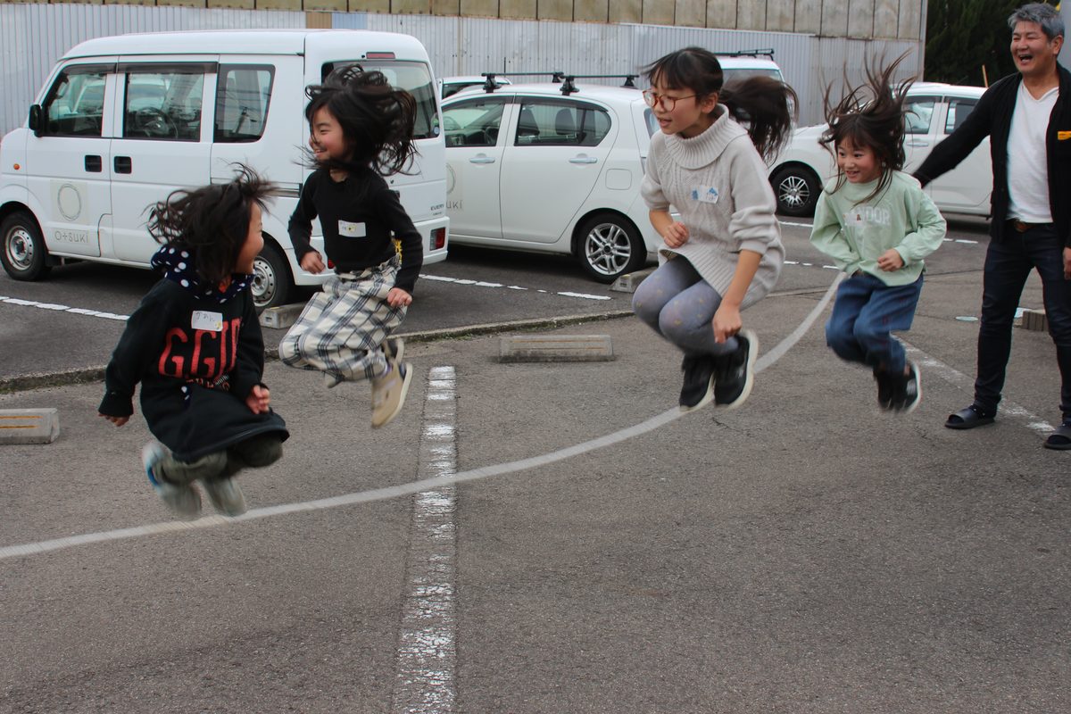 外で大縄跳びをする子どもたち